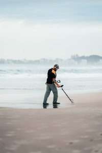 man on beach metal detecting