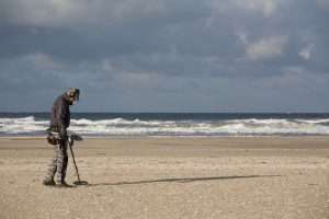 man on beach with metal detector, beachcombing