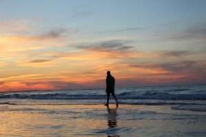 man walking beach at sunset, beachcombing, relaxing