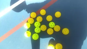 numerous yellow pickleballs on a court